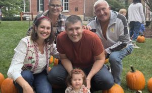 Family picks pumpkin in front of Peck House